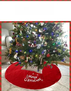 Close-up of red plush Christmas tree skirt with white Merry Christmas embroidery
