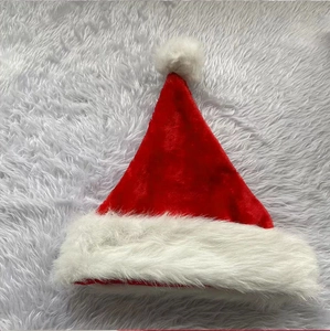 Detail of red short plush Christmas hat with fluffy white faux fur trim and soft pompom