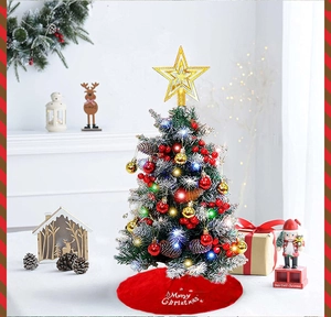 Close-up of mini Christmas tree with LED lights, golden star and red Merry Christmas skirt