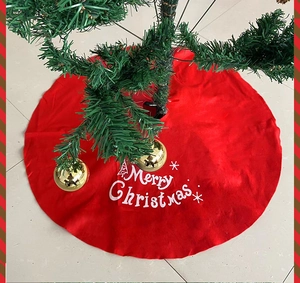 Close-up of red Christmas tree skirt featuring white Merry Christmas text and snowflake patterns