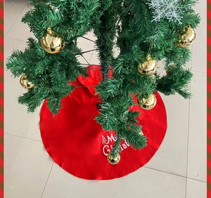 Detail of red Merry Christmas tree skirt with white festive lettering and tree patterns