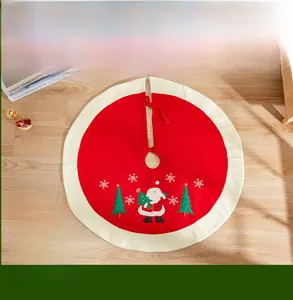 Detail of red Christmas tree skirt featuring Santa Claus embroidery and white ruffled edge