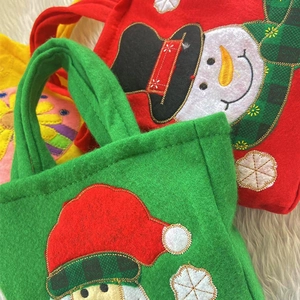 Detailed close-up of colorful felt Christmas gift bags with snowman and Santa embroidery