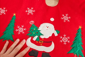 Detail of red Christmas tree skirt with festive Santa Claus and snowflake embroidery