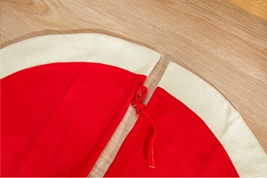 Detail of red knitted Christmas tree skirt featuring white border and tie-up closure strings