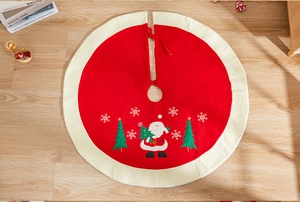 Detail of red and white Christmas tree skirt with embroidered Santa and snowflakes pattern