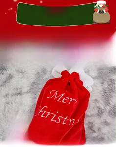 Close-up of red velvet Christmas gift bag with white Merry Christmas embroidery and pom-poms