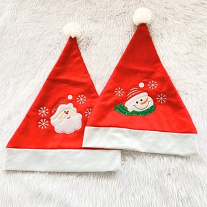 Detail of embroidered Santa and Snowman motifs on plush red velvet Christmas hats