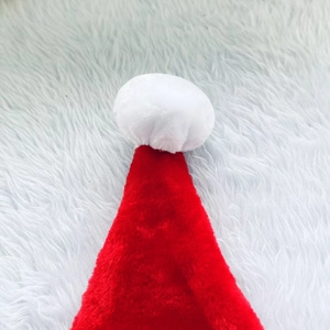 Close-up of the soft plush white pom-pom detail on top of a red velvet Christmas hat