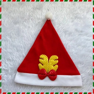 Christmas hat with golden sequin antlers and red bow on white plush background