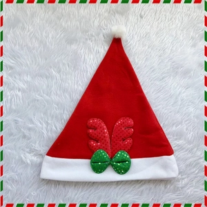 Detail view of a red sequin reindeer antler Christmas hat with green bow and plush trim