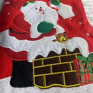 Detailed close-up of Santa Claus embroidery on a festive red fabric Christmas stocking