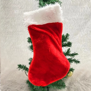 Classic red plush Christmas stocking with white trim hanging on a festive tree branch
