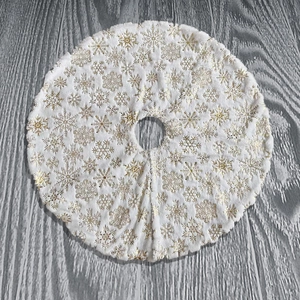 Close-up of white plush Christmas tree skirt with gold foil snowflake patterns