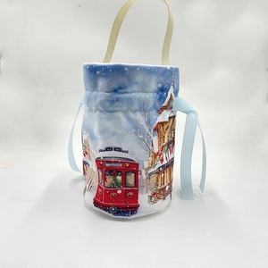 Close-up of a festive velvet drawstring gift bag with a vintage tram and snow scene print