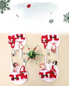 Close-up of knitted Santa suit cutlery holders with forks and spoons on a white plate