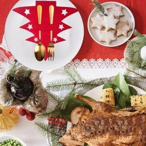 Christmas tree shaped red felt cutlery holders with star patterns on a festive table