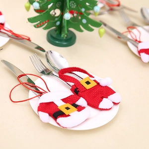 Christmas themed Santa outfit cutlery set holder on a white plate with holiday decor