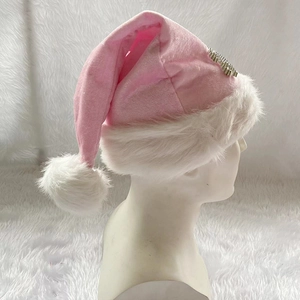 Detail eines rosa Plüsch-Weihnachtshutes mit weißem Besatz und silbernem Merry-Anhänger