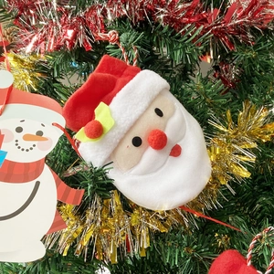 Detail of plush Santa Claus pendant and snowman tag hanging on a Christmas tree branch