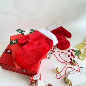 Gros plan de moufles de Noël en velours rouge avec bordure en peluche sur boîte cadeau