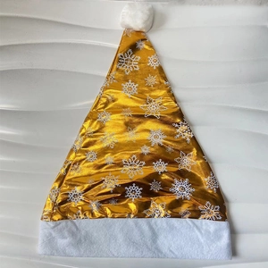 Detail of shiny gold Christmas hat featuring white snowflake patterns and plush trim