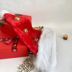 Détail du bonnet de Noël en peluche rouge avec cloches dorées sur boîtes cadeaux