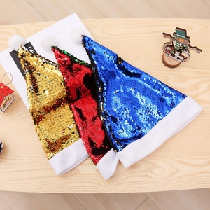Tre cappelli natalizi di paillettes con bordo in pelliccia bianca su tavolo in legno