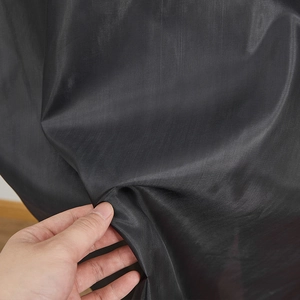 Gros plan sur le tissu synthétique noir montrant la texture et le tissage de la cape d'Halloween