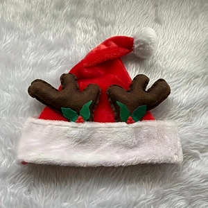 Detailed close-up of a red plush Christmas hat with brown antlers and holly berry decor