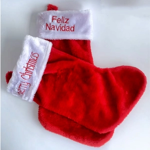 Detail of red plush Christmas stockings with Merry Christmas and Feliz Navidad embroidery