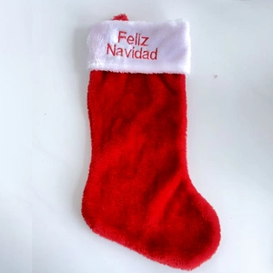 Detail of red Christmas stocking with white plush cuff and Feliz Navidad embroidery