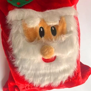 Close-up of plush Santa Claus face and white faux fur on the red Christmas gift bag