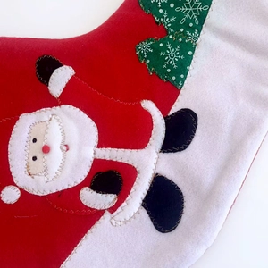 Red and white Christmas stocking featuring handmade felt Santa Claus and green tree decor