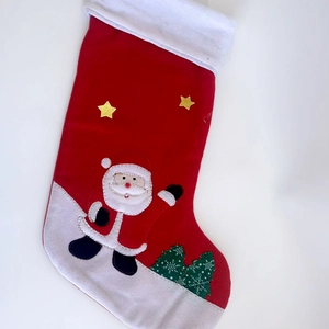 Classic red and white Christmas stocking with embroidered Santa Claus and green tree hanging