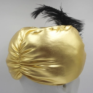 Detail eines metallischen goldfarbenen Turbans mit langer schwarzer Feder und Faltenwurf