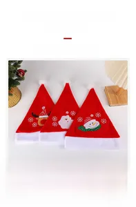 Dettaglio ravvicinato di tre cappelli natalizi in peluche con ricami di Babbo Natale e renna