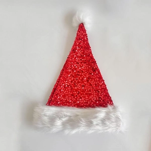 Flat lay of shimmering red sequin Christmas hat with soft white plush trim and pompom