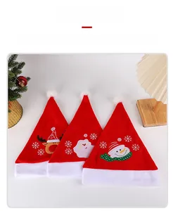 Dettaglio di tre cappelli di Natale in velluto rosso con ricami di renne e pupazzi di neve