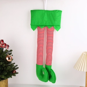 Weihnachtliche Elf-Beine Dekoration mit rot-weißen Streifen neben einem Weihnachtsbaum