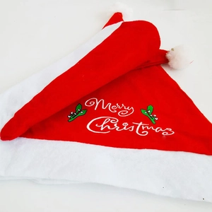Dettaglio cappello di Natale rosso con scritta Merry Christmas e motivo a bacche verdi