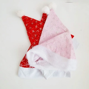 Dettaglio di cappelli di Natale rossi e rosa con fiocchi di neve argentati e bordo in pelliccia