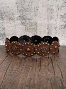 Detail of vintage brown leather belt with bull head studs and brass rivets on wood