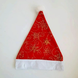 Vista piatta di un cappello di Natale rosso con fiocchi d'oro e bordo in pelliccia bianca