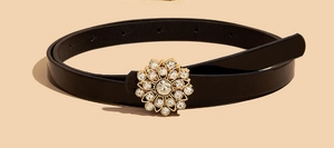 Vue détaillée d'une ceinture fine en cuir verni noir pour enfant avec boucle à strass fleurie