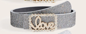 Dettaglio della cintura di lusso con strass e fibbia argentata con scritta Love lucida