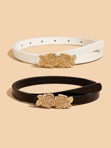 Dettaglio di cinture sottili nere e bianche con fibbie in metallo a forma di rosa dorata vintage