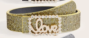 Dettaglio della cintura in strass glitter oro con fibbia in metallo incisa Love