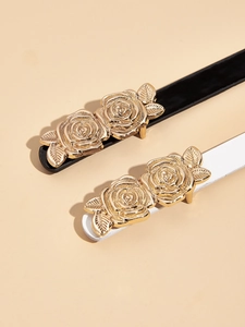 Dettaglio delle eleganti fibbie in metallo rosa dorato su cinture sottili nere e bianche