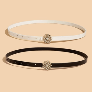 Détail de ceintures fines noires et blanches avec boucles fleurs dorées et strass